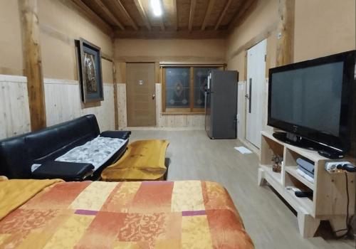 a living room with a bed and a flat screen tv at Haneul Cheon Ddaji Hanok in Yangyang