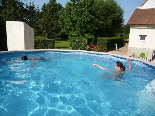 2 personnes nagent dans une piscine dans l'établissement Maison spacieuse avec jardin clos, piscine privative et sauna, proche centre de Saint-Pourçain - FR-1-489-60, à Saint-Pourçain-sur-Sioule
