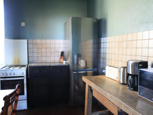 a kitchen with a refrigerator and a wooden table at Grande Ferme avec Piscine Privative et Jardin, Proche Étang, Chappes - FR-1-489-90 in Chappes