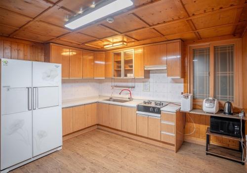a kitchen with wooden cabinets and a white refrigerator at Yongin Yejik Hanok Pension in Yongin