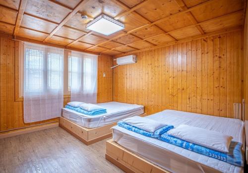 two beds in a room with a wooden ceiling at Yongin Yejik Hanok Pension in Yongin