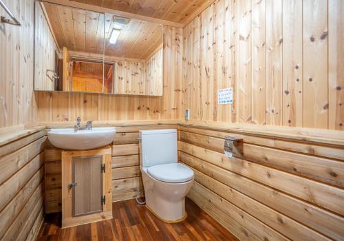 a wooden bathroom with a toilet and a sink at Yongin Yejik Hanok Pension in Yongin