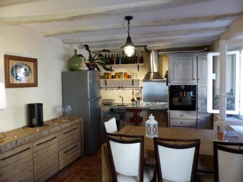 Il comprend une cuisine équipée d'un réfrigérateur et d'une table avec des chaises. dans l'établissement Gîte chaleureux à la ferme près de Vulcania avec jardin et activités enfants - FR-1-489-166, à Vicq