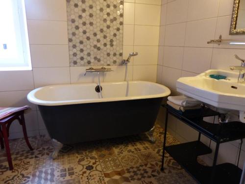 a bath tub and a sink in a bathroom at Gîte chaleureux à la ferme près de Vulcania avec jardin et activités enfants - FR-1-489-166 in Vicq