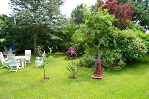 a garden with chairs and a table and a windmill at Friesenhof Nieblum - Hotel Garni in Nieblum