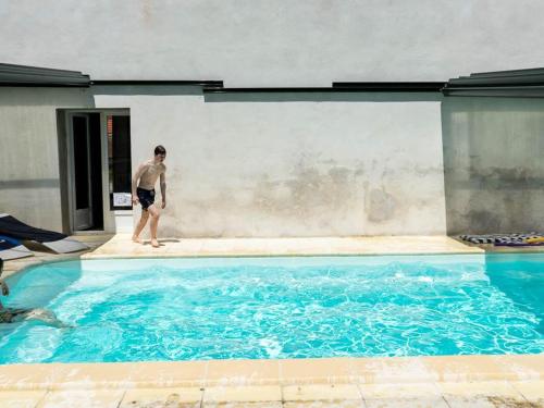 un homme debout à côté d'une grande piscine dans l'établissement Gîte familial en ferme équestre avec piscine, nature et confort à Souvigny - FR-1-489-466, à Souvigny