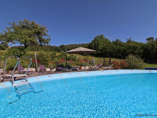 une grande piscine avec des chaises et un parasol dans l'établissement Maison isolée avec spa nordique, piscine et jardin privatif au cœur de la nature - FR-1-497-116, à La Lande-de-Goult