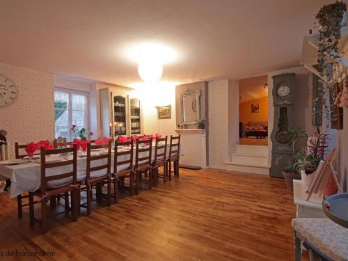 une salle à manger avec une longue table avec des fleurs rouges dessus dans l'établissement Gîte familial tout confort avec jeux et jardin, proche voie verte et rivière - FR-1-497-132, à Dompierre