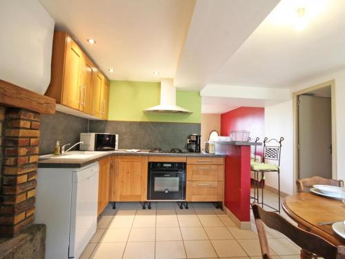 a kitchen with wooden cabinets and a table in it at Maison Normande avec Jardin Clôturé, Cheminée et Options Confort, près de la Roche d'Oëtre - FR-1-497-141 in Frênes
