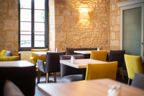 a dining room with tables and yellow chairs at Hôtel La Couleuvrine Sarlat Centre Ville in Sarlat-la-Canéda