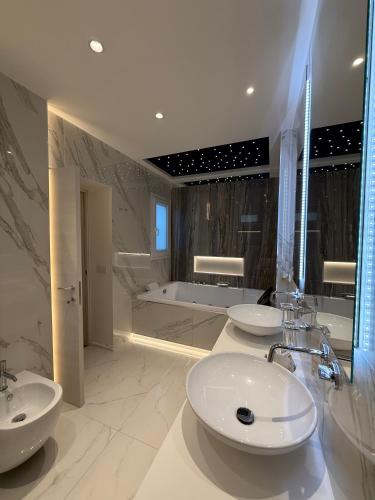 a bathroom with three sinks and a bath tub at Saretta Luxury Suites in Cagliari