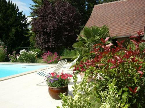 un patio avec une piscine, des chaises et des fleurs dans l'établissement Maison individuelle à Contres avec piscine partagée - FR-1-491-465, à Le Controis En Sologne