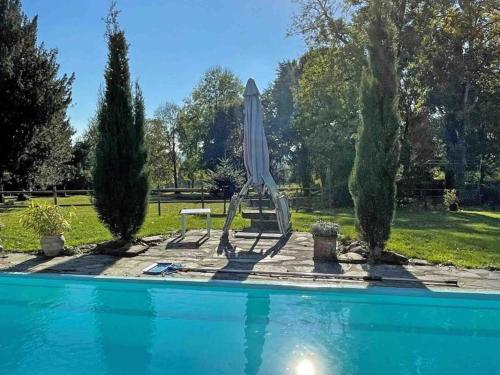 - une piscine bleue avec un parasol et une table dans l'établissement Gîte tout confort avec piscine chauffée, jardin et terrasse, idéal pour curistes et randonneurs - FR-1-497-199, à La Chapelle d'Audaine