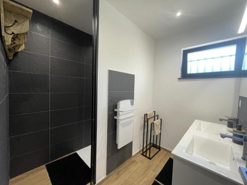 La salle de bains est pourvue d'une douche et d'un lavabo blanc. dans l'établissement Gîte cosy en forêt avec terrasse, proche étang et loisirs, 3 chambres, wifi, plancha et parking - FR-1-489-453, à Cérilly