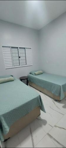 a bedroom with two beds and two windows at Ótimo Apartamento 2 quartos mobiliado in Silvânia