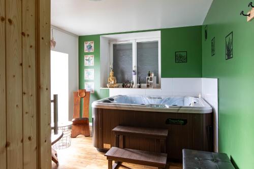 a bathroom with a large tub and green walls at Gîte Chabrignac, jacuzzi et sauna privatif, piscine chauffée partagée, Wifi, salle de jeux in Beynat