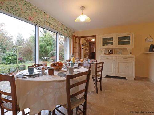 a dining room with tables and chairs and a large window at Retraite paisible en maison traditionnelle, 4 chambres, jardin arboré, cheminée et nature luxuriante. - FR-1-497-154 in Saint-Cornier-des-Landes