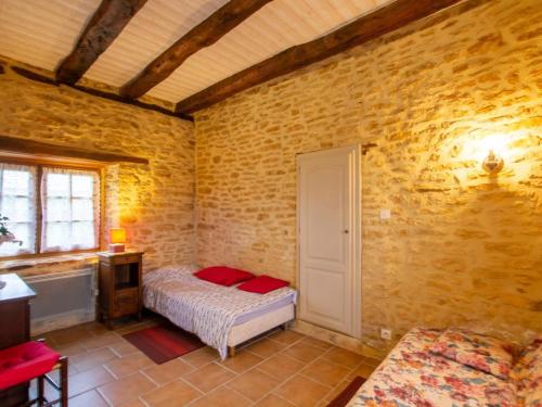 une chambre avec un lit dans un mur de briques dans l'établissement Maison rustique avec jardin et équipements pour enfants, proche Sarlat - FR-1-616-394, à Marcillac-Saint-Quentin