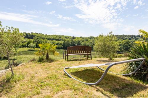 a wooden bench sitting in the grass with a hose at Gîte Chabrignac, jacuzzi et sauna privatif, piscine chauffée partagée, Wifi, salle de jeux in Beynat