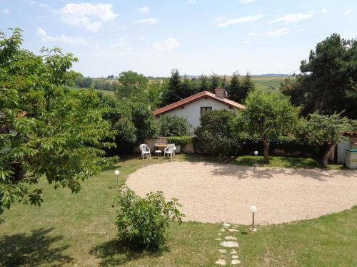 a garden with a table and chairs in front of a building at Charmant Gîte dans les Monts du Lyonnais avec Jardin, Terrasse et Confort Moderne - FR-1-496-174 in Maringes