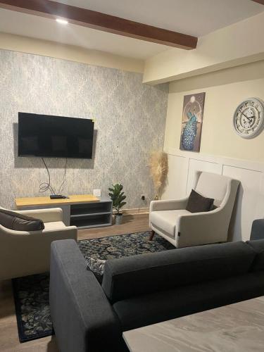 a living room with a couch and chairs and a tv at Cozy comfort apartment in Lusaka