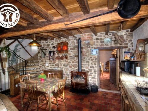 une salle à manger avec une table et une cheminée en pierre dans l'établissement Gîte charmant avec four à pain, jardin, terrasse, jeux et poêle à bois, acceptant animaux - FR-1-496-137, à Chirassimont