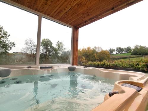 a hot tub in a room with large windows at Gîte de charme avec spa, terrasse et balcon - Tout confort, au cœur de la nature - FR-1-496-303 in Pouilly-les-Feurs