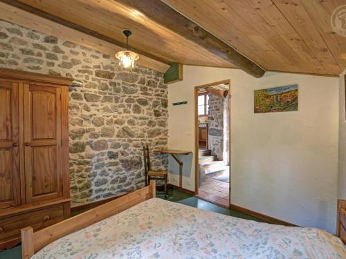 sypialnia z łóżkiem i kamienną ścianą w obiekcie Gîte Écologique à 10 min des Pistes avec Wi-Fi et Environnement Calme - FR-1-496-98 w mieście Mermond