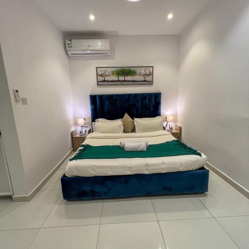 a bedroom with a large bed with a blue headboard at Superior Furnished Apartments شقق مخدومة فاخرة in Jeddah