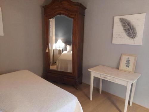 a bedroom with a mirror and a bed and a table at Gîte chaleureux avec poêle à bois, terrasse, wifi, proche activités nature - FR-1-496-268 in Saint-Régis-du-Coin