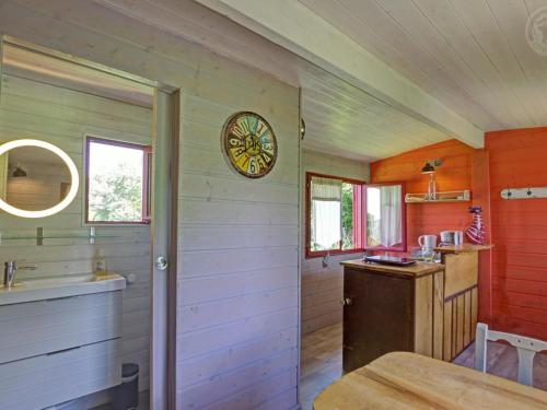 une cuisine avec une table et une horloge au mur dans l'établissement Roulotte du Chat qui Pète: Séjour Paisible et Animaux Bienvenus - FR-1-496-308, à Saint-Germain-Lespinasse