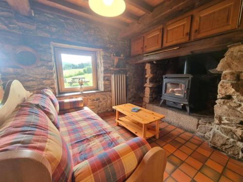 Una sala de estar con un sofá y una estufa de leña. en Gîte familial dans le massif du Pilat avec confort inclus - FR-1-496-294, en Doizieux