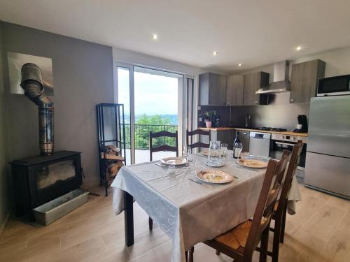 - une cuisine avec une table, des chaises et une cuisinière dans l'établissement Gîte rénové avec terrasse panoramique et tout confort à Saint-Chamond, proche Saint-Étienne et Lyon - FR-1-496-324, à Saint-Chamond
