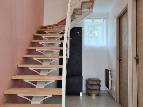 a wooden spiral staircase in a home with pink walls at Maison spacieuse avec jardin, près de Disneyland et Reims, idéale pour familles et amis - FR-1-532-22 in Viels-Maisons