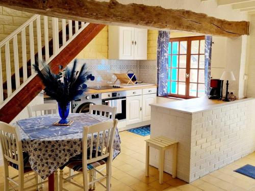 une cuisine avec une table avec un vase dessus dans l'établissement Gîte charmant au bord de l'eau avec terrasse, cheminée et équipements complets à Lesquielles-St-Germain - FR-1-532-18, à Guise