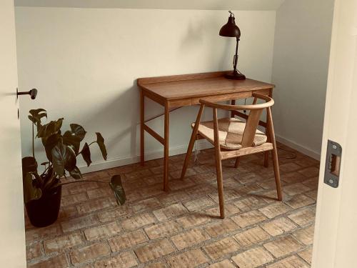 a desk with a chair and a lamp and a plant at Modernized A-Frame House Near Saksild Beach in Odder
