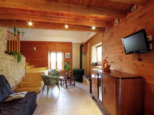 a living room with a couch and a tv at Maison cosy avec spa, sauna et lamas à proximité de Roanne - FR-1-496-23 in Saint-André-dʼApchon