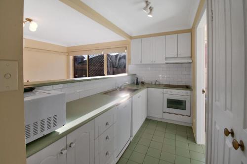 una cucina con mobili bianchi e un lavandino di Central Escape - Walk to CBD, Cosy & Convenient a Wagga Wagga
