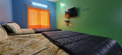 a bedroom with two beds and a flat screen tv at PK Residency in Yelagiri