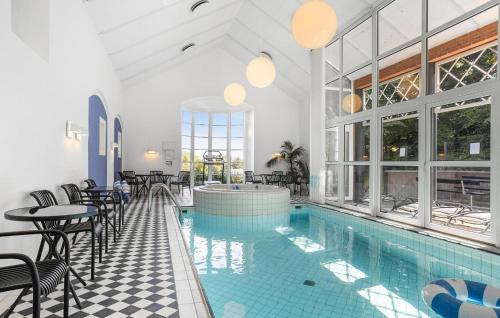 a swimming pool with tables and chairs in a building at Five Bedroom Beautiful Home In Sindal in Sindal