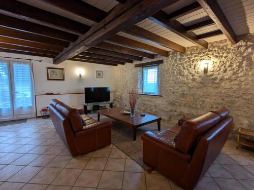 a living room with leather furniture and a tv at Gîte spacieux avec piscine chauffée, jardin, WIFI et animaux admis - FR-1-653-273 in Angeduc