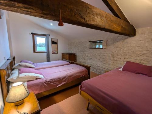 a bedroom with two beds and a stone wall at Gîte spacieux avec piscine chauffée, jardin, WIFI et animaux admis - FR-1-653-273 in Angeduc