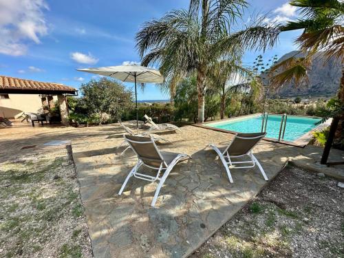 a table with chairs and an umbrella next to a pool at VILLA MÀRCATO tra Monti & Mare in San Vito lo Capo