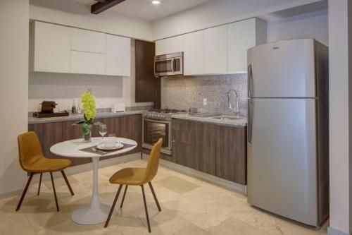a kitchen with a white refrigerator and a table and chairs at MX Grand Suites in Mexico City