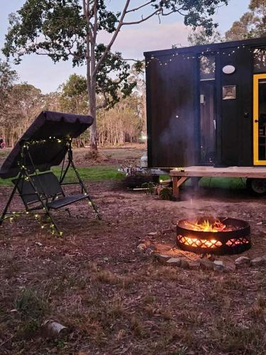 a fire pit in front of a camping trailer at Woodlands by Tiny Away in Howard