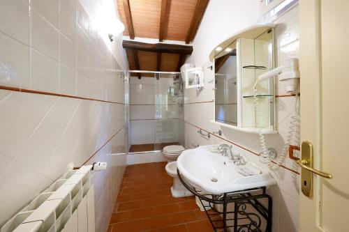 a bathroom with a sink and a toilet and a mirror at Historic Villa Overlooking Lake Trasimeno in Paciano