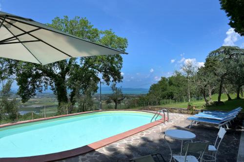 a swimming pool with an umbrella and a table and chairs at Historic Villa Overlooking Lake Trasimeno in Paciano