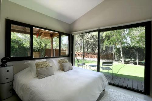 Schlafzimmer mit einem weißen Bett und großen Fenstern in der Unterkunft Superb Contemporary Villa Near Montpellier in Castelnau-le-Lez