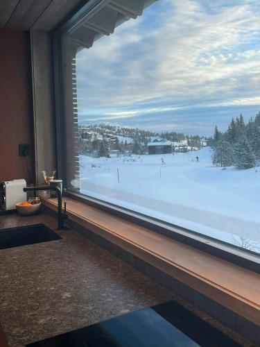 a room with a large window looking out at a snow covered field at Architect Designed Mountain Cabin At Kvitfjell in Favang