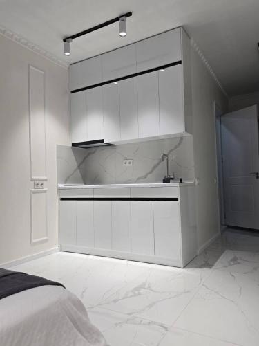 a white kitchen with white cabinets in a bedroom at Real Palace Apartment in Batumi